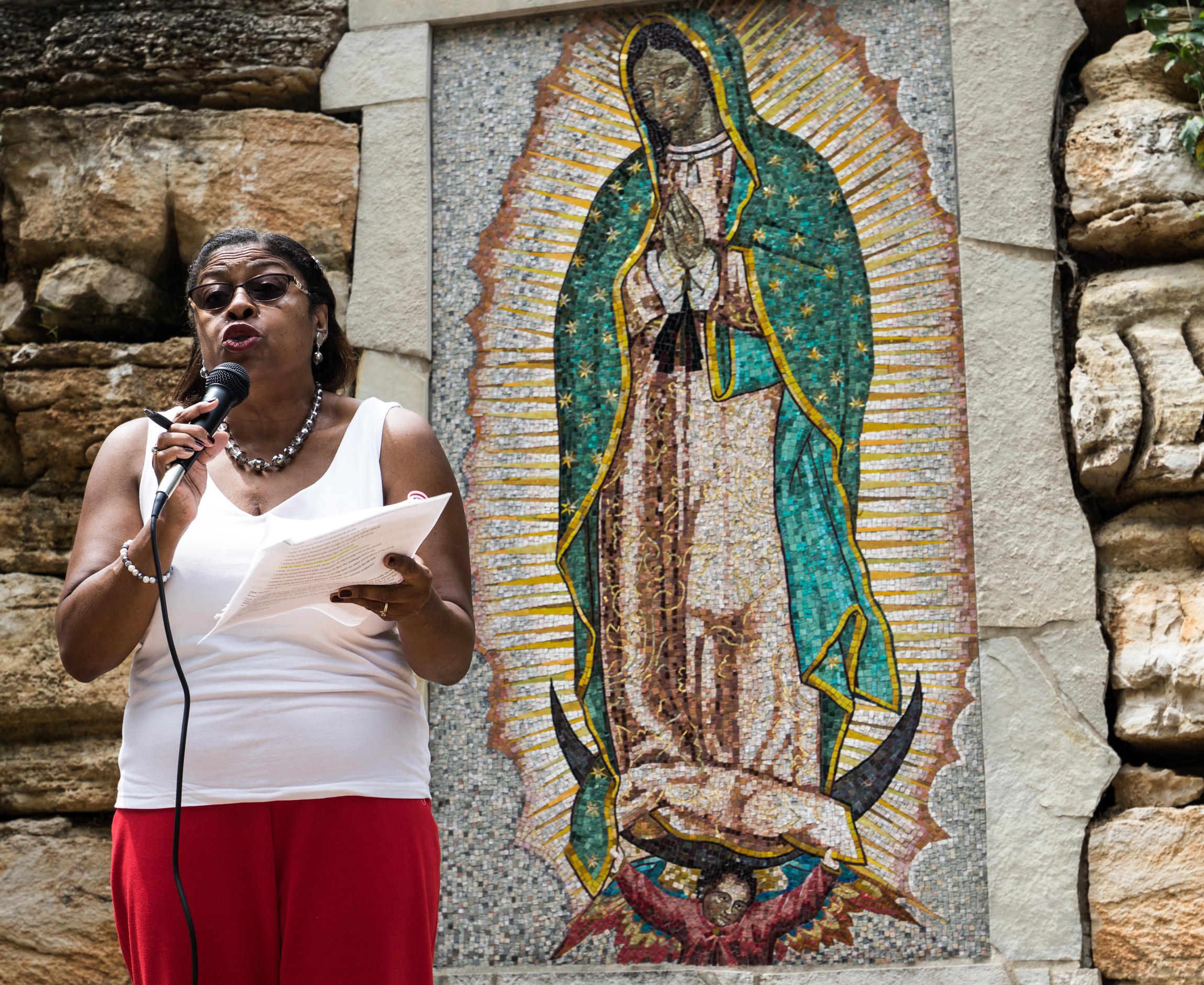A woman speaks during an Aug. 5 ecumenical prayer service at grotto at Our Lady of Guadalupe Church in Ferguson, Mo. The service commemorated the first anniversary of the shooting death of 18-year-old Michael Brown. (CNS photo/Weston Kenney, St. Louis Review)