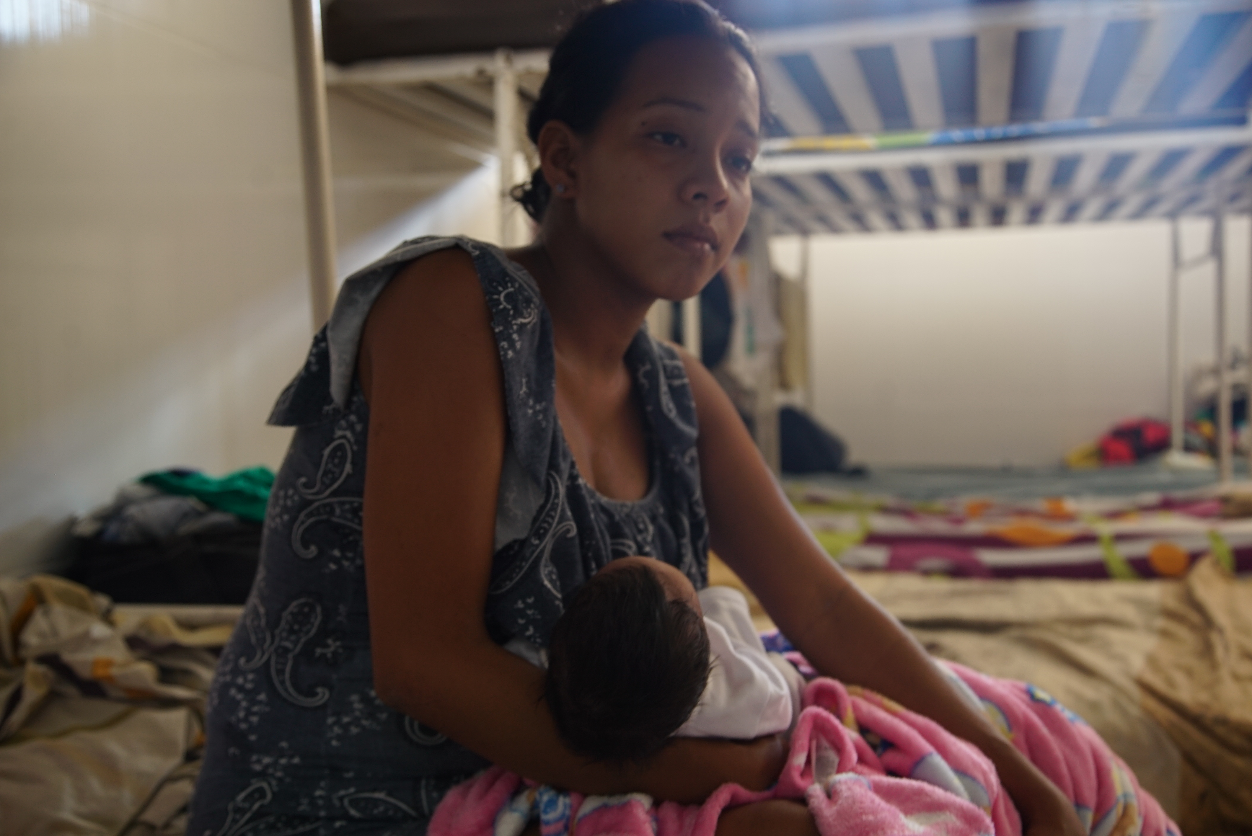 Jenny holds her newborn on her bed in the Scalabrini-run migrant shelter in Cucuta. Photo by Antonio De Loera-Brust
