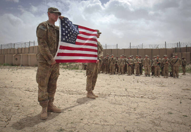 U.S. soldier hold American flag during Memorial Day ceremony in Afghanistan. (CNS photo/Danish Siddiqui, Reuters)