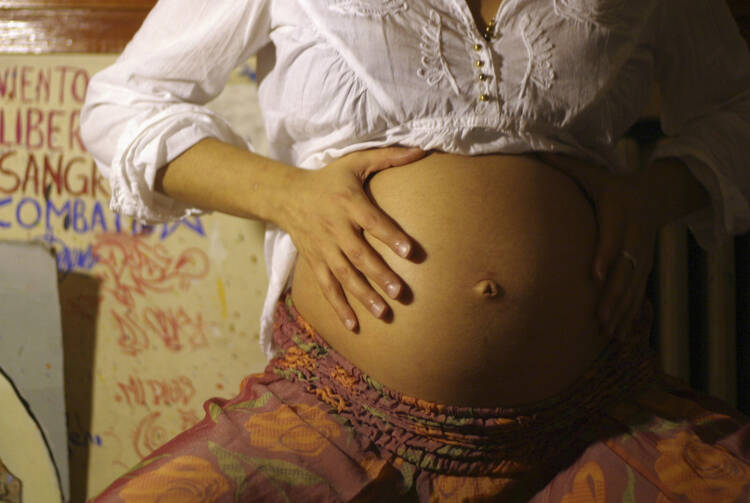 A pregnant woman touches her stomach at her home in Buenos Aires, Argentina. (CNS photo/Reuters)