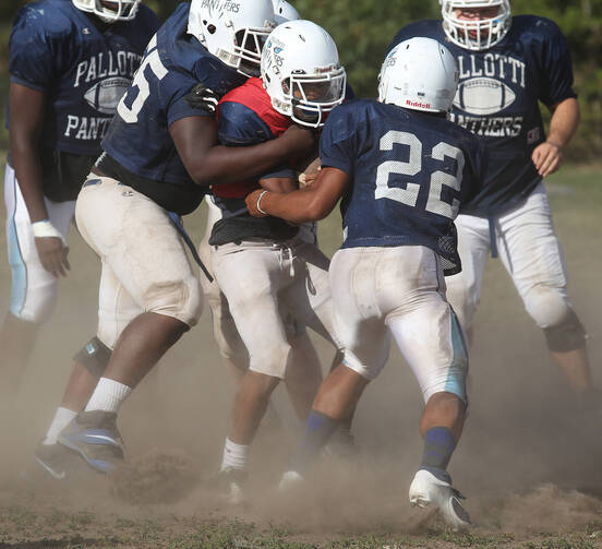 Players converge on quarterback during football practice at Maryland Catholic high school. (CNS photo /Bob Roller) 