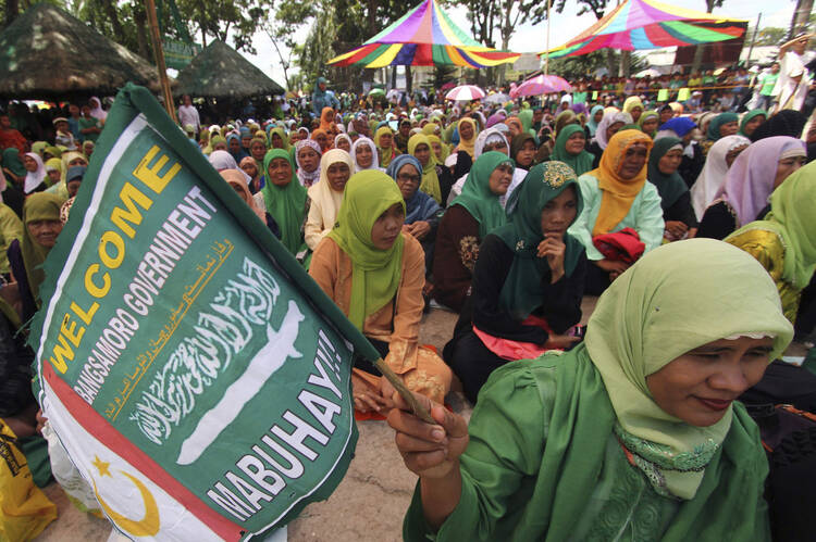 A Moro woman holds a flag of the Moro Islamic Liberation Front during a gathering in southern Philippines.
