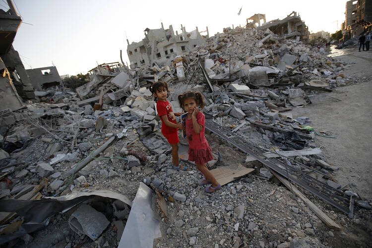 Sisters walk among the rubble of destroyed home in Gaza Strip. (CNS photo/Mohammed Saber, EPA)