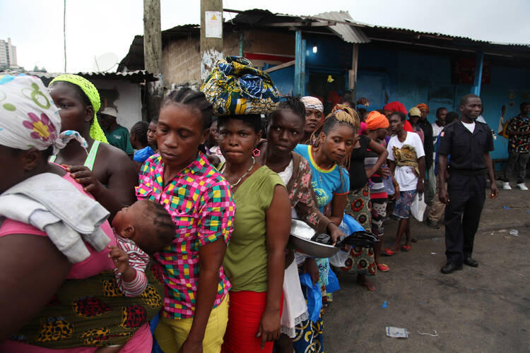 Residents of the West Point neighborhood of Monrovia, Liberia, wait for food rations to be handed out Aug. 21 as part of the government's quarantine plan for the area to fight the spread of the Ebola virus. (CNS photo/Ahmed Jallanzo, EPA)