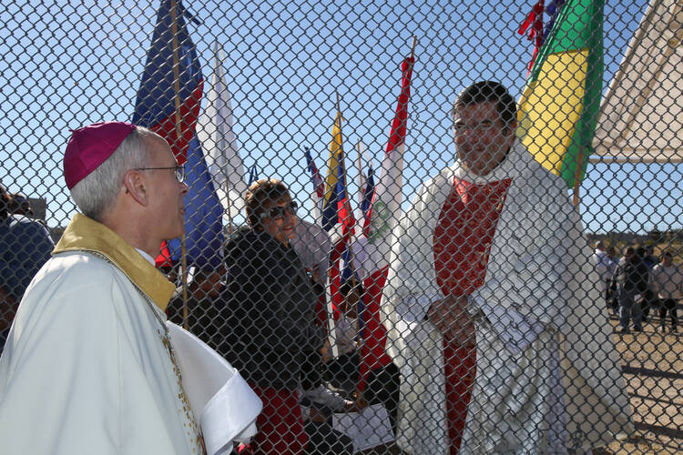 Bishop Mark J. Seitz of El Paso, Texas, right, talks through the border fence to Msgr. Jose Rene Planco of Juarez, Mexico, before a Mass Nov. 22 in Sunland Park, N.M., at the Mexican border. (CNS photo/Bob Roller)