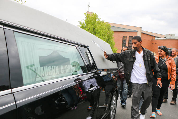 A mourner pats the hearse holding the casket of Freddie Gray outside New Shiloh Baptist Church in West Baltimore on April 27. (CNS photo/Olivia Obineme, Catholic Review)