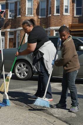 West Baltimore residents sweep broken glass and debris outside a store damaged by rioters earlier this week. (CNS photo/Karen Osborne, Catholic Review)