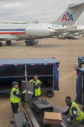 An American Airlines ground crew unloads baggage at Dallas/Fort Worth Airport in late March. Labor Day, honoring working people of America, is observed Sept. 7 this year. (CNS photo/Jim West)