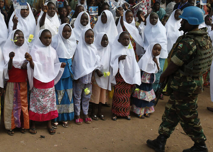 An U.N. peacekeeper stands guard as children wait for Pope Francis' arrival for a meeting with the Muslim community at the Koudoukou mosque in Bangui, Central African Republic, Nov. 30. (CNS photo/Paul Haring)