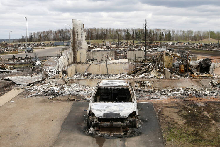 A charred vehicle and home are pictured in the burned-out Beacon Hill neighborhood of Fort McMurray, Alberta, May 9, after wildfires forced the evacuation of the entire town. (CNS photo/Chris Wattie, Reuters)
