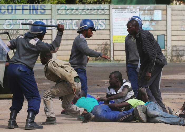 Riot police detain residents after a July 4 protest by taxi drivers turned violent in Harare, Zimbabwe. Violent protests in Zimbabwe reflect people's frustrations in extremely difficult times, a church official said. (CNS photo/Philimon Bulawayo, Reuters)
