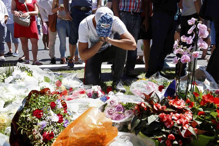 A man prays in front of a makeshift memorial July 15 in Nice, France, as people pay tribute near the scene where a truck ran into a crowd killing more than 80 people the previous evening. (CNS photo/Pascal Rossignol, Reuters) 