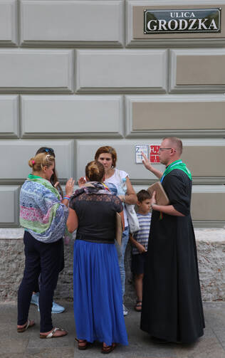 A priest prays over pilgrims along a street on July 24 in Krakow, Poland, ahead of World Youth Day. (CNS photo/Bob Roller)