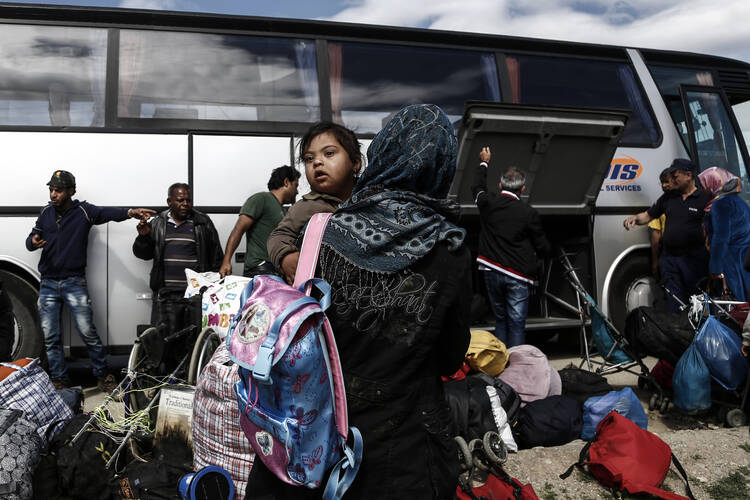 Syrian refugees stand outside a bus at a refugee camp near Idomeni, Greece, May 25. (CNS photo/Yannis Kolesidis, EPA) 