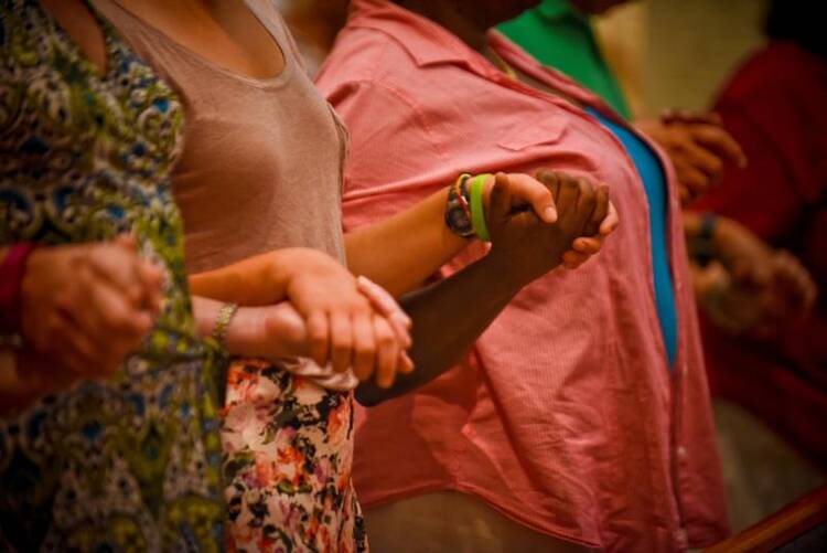 Congregants hold hands and pray for peace during Mass at All Saints Church in Milwaukee Aug. 18. 