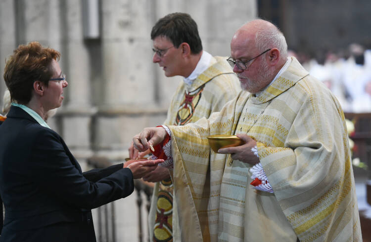 Cardinal Rainer Maria Woelki of Cologne, Germany, and Cardinal Reinhard Marx of Munich and Freising distribute Communion during Cardinal Woelki's installation Mass at the cathedral in Cologne on Sept. 20, 2014. (CNS photo/Jorg Loeffke, KNA) 