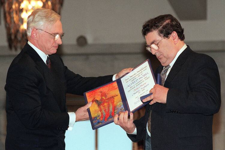 In this Dec. 10, 1998 file photo, John Hume, right, looks at the Nobel Peace Prize diploma which he received from Francis Sejersted, left, chairman of the Norwegian Nobel Peace Prize Committee during the award ceremony in Oslo Town Hall. (AP Photo/Bjoern Sigurdsoen/NTB/POOL)
