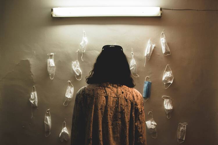 a woman looks at a wall with face masks hanging on it