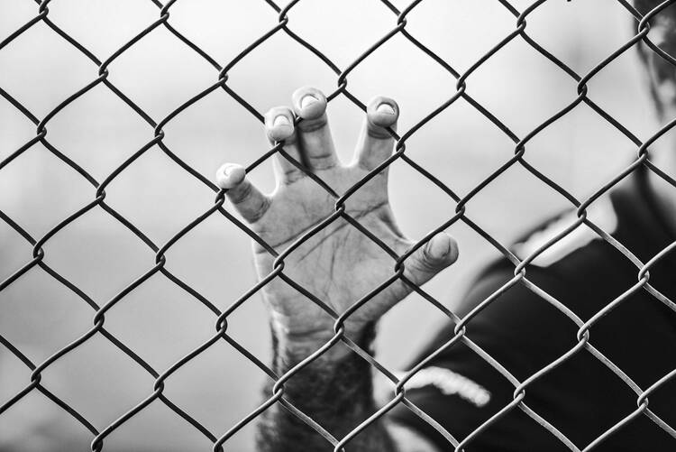 man holding chain link fence