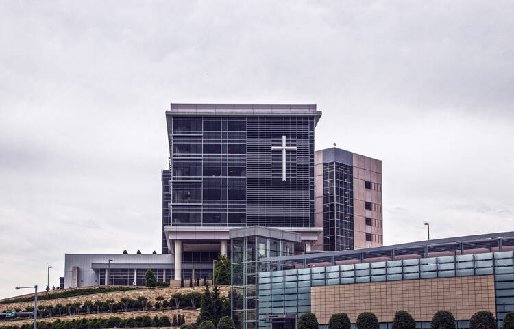 St Francis Hospital in Tulsa, Oklahoma, seen from below on a landscaped hill with a giant cross on the front windows (iStock/Susan Vineyard)
