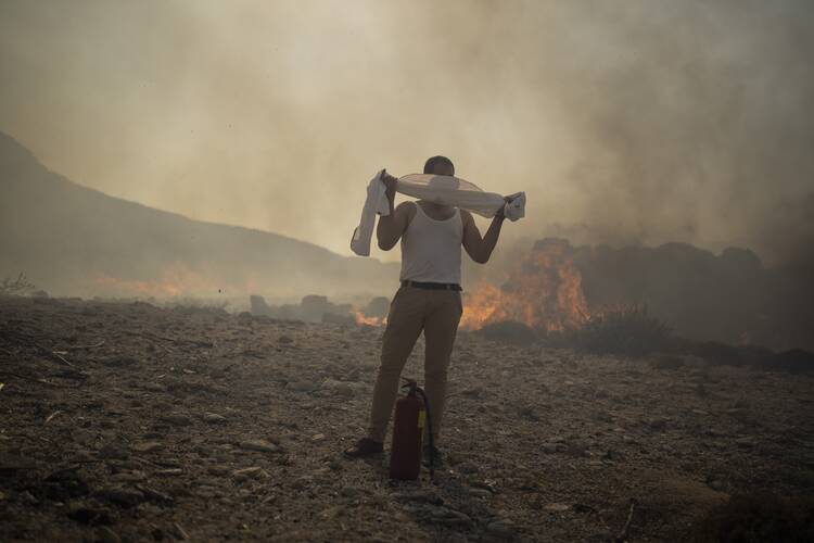 A man wraps his shirt over his face as he tries to extinguish a fire, near the seaside resort of Lindos, on the Aegean Sea island of Rhodes, southeastern Greece, on July 24, 2023. Among other regions, Europe is facing growing climate risks and is unprepared for them, the European Environment Agency said on March 11, 2024. (AP Photo/Petros Giannakouris, File)