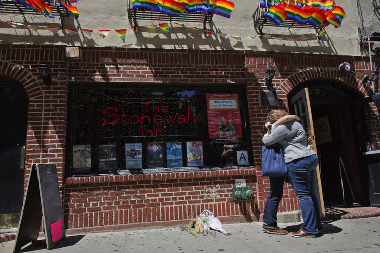 A couple embraces outside the Stonewall Inn in New York on June 12, 2016. An L.G.B.T. ministry plans to hold a Mass on June 27 outside the bar considered the birthplace of the L.G.B.T. civil rights movement. (AP Photo/Mary Altaffer, File)