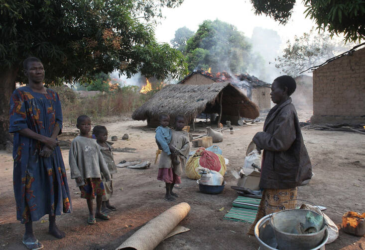 Women and children stand near their destroyed house in a village in Bossangoa, Central African Republic