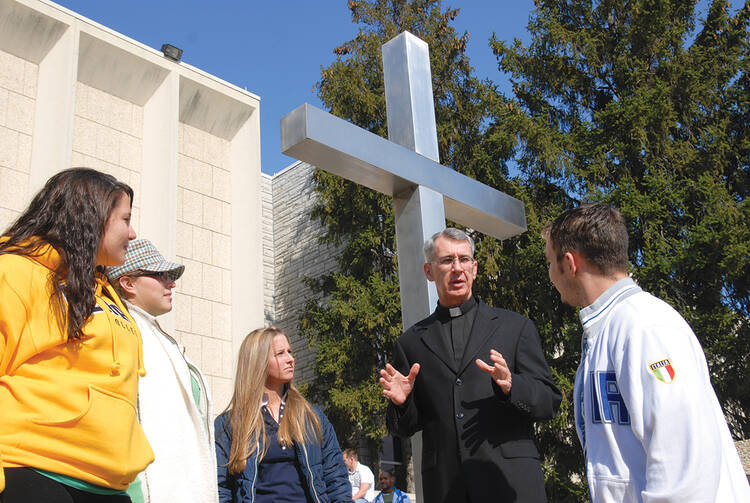 TRUE DIALOGUE. The Rev. Philip Lowe, chaplain of Neumann University in Aston, Pa., with students outside the campus chapel.