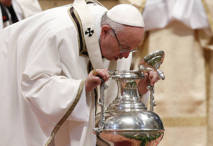 Pope Francis breathes over chrism oil, a gesture symbolizing the infusion of the Holy Spirit, during the Holy Thursday chrism Mass in St. Peter's Basilica at the Vatican, March 24 (CNS photo/Paul Haring).