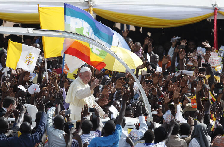 The Vatican flag and a peace banner are seen as Pope Francis greets the crowd as he arrives for a meeting with young people at the Kololo airstrip in Kampala, Uganda, Nov. 28 (CNS photo/Paul Haring). 