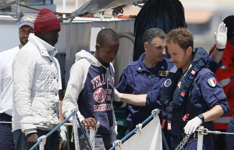 Italian coast guards instruct immigrants as they disembark from a coast guard ship at port in Lampedusa, Italy