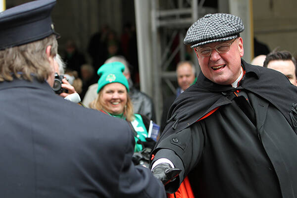 Cardinal Timothy M. Dolan of New York greets a New York City firefighter while reviewing the 253rd annual St. Patrick’s Day parade in front of St. Patrick’s Cathedral in New York on March 17, 2014. RNS photo by Gregory A. Shemitz