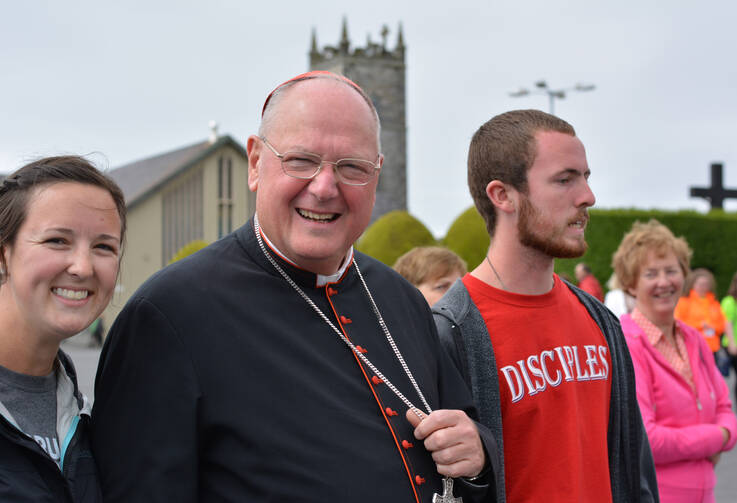 Cardinal Timothy M. Dolan of New York stands with Franciscan University of Steubenville students who came to see the cardinal open the novena in Knock, Ireland, Aug. 14. (CNS photo/Sarah Mac Donald) 