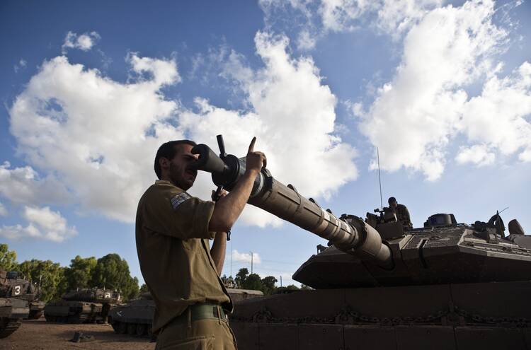 An Israeli soldier adjusts the barrel of a tank at a military staging area outside the northern Gaza Strip on July 14. 