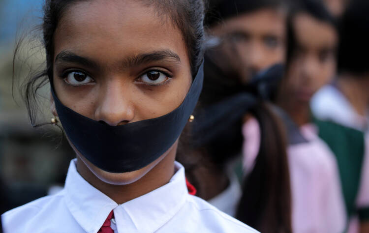 A student tapes her mouth shut during a March 16 candlelight vigil for an elderly nun who was raped in Ranaghat, India. (CNS photo/Piyal Adhikary, EPA)