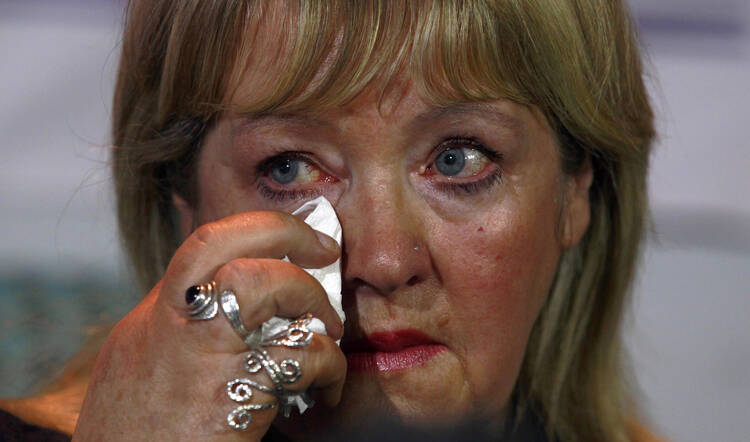 Woman who worked in a Magdalen laundries wipes tear during news conference in Dublin, Feb. 2013.