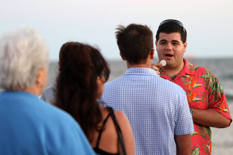 ALL ARE WELCOME. Seminarian Matt Browne distributes Communion during a beach Mass in Long Beach, N.Y., Sept. 6 (CNS photo/Gregory A. Shemitz, Long Island Catholic). 