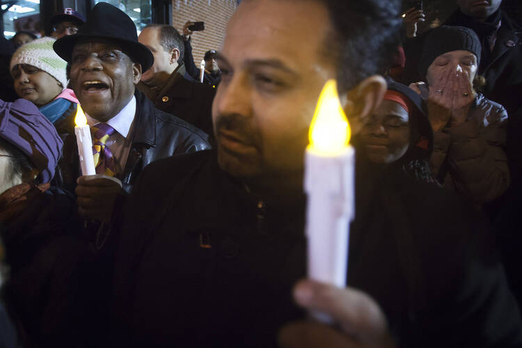 Community members join a prayer vigil on Dec. 22 at the site of the officers' murder in Brooklyn. (CNS photo/Carlo Allegri, Reuters) 