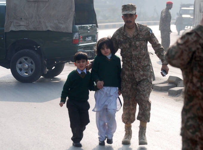 A soldier escorts schoolchildren from the Army Public School attacked Dec. 16 by Taliban gunmen in Peshawar, Pakistan. (CNS photo/Khuram Parvez, Reuters)
