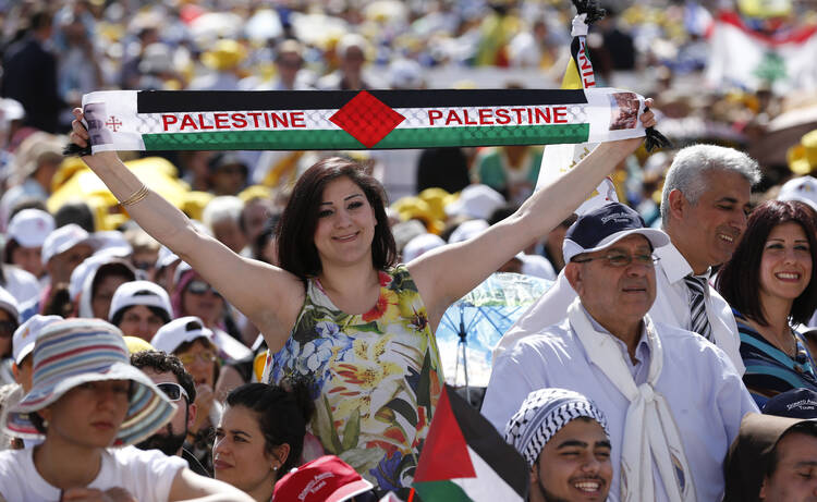A woman holds a banner with the colors of the Palestinian flag before the start of the canonization Mass for four new saints celebrated by Pope Francis in St. Peter's Square at the Vatican May 17. (CNS photo/Paul Haring)