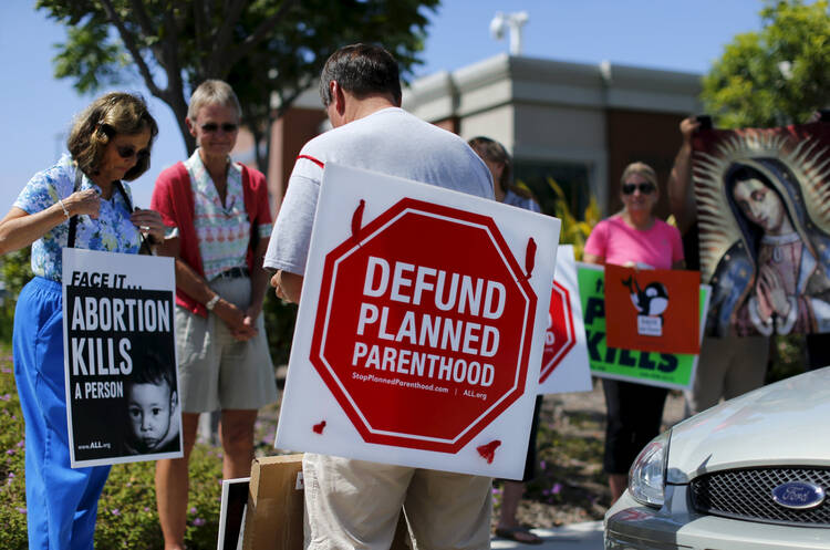 Protesters carry signs and an image of Our Lady of Guadalupe outside a Planned Parenthood clinic in Vista, Calif., Aug. 3 (CNS photo/Mike Blake, Reuters). 