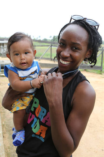 Ibukun Akinboyo of Trinadad, a resident at Johns Hopkins Hospital in Baltimore, holds a child outside a clinic in Akawini, Guyana, in March. (CNS photo/Bob Roller)