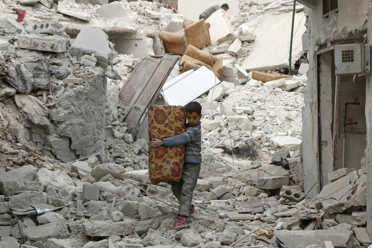 A boy walks on the rubble of damaged buildings in Aleppo, Syria in November 2014. (CNS photo/Hosam Katan, Reuters) 