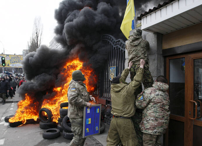 Servicemen from the Aydar battalion throw a Ukrainian flag from the building of Ukraine's Defense Ministry in Kiev during a protest against the disbanding of the battalion in this file photo. (CNS photo/Valentyn Ogirenko, Reuters) 