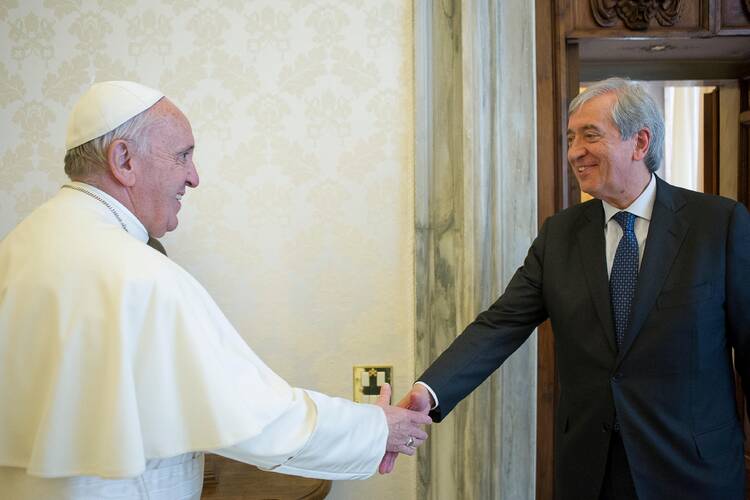 Pope Francis wearing his white robes shakes hands with Libero Milone, dressed in a black suit