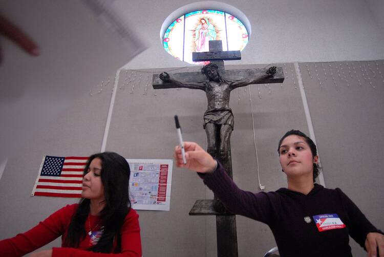Election poll worker Indira Barrios, 17, loans a pen to a voter at the La Quinta de Guadalupe retreat and conference center in San Diego on Nov. 4, 2008. (CNS photo/David Maung)