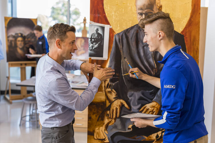 Jeremy Caniglia, an art teacher at Creighton Preparatory School, instructs Michael Bope on a painting of Pedro Arrupe, S.J.