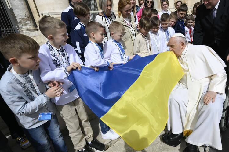 Pope Francis kisses a Ukrainian flag carried by a group of Ukrainian children attending his weekly general audience in St. Peter's Square at the Vatican on April 10, 2024. (CNS photo/Vatican Media)