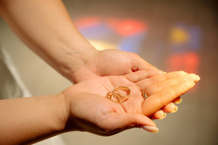 A close-up photo of wedding rings in the palm of a hand that is resting on the palm of another hand (iStock/Alexandr Baitelman)