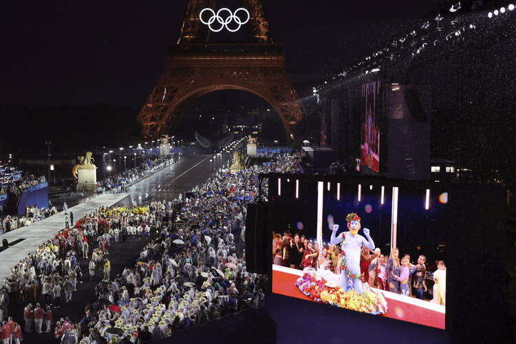 Delegations arrive at the Trocadero as spectators watch French singer Philippe Katerine performing on a giant screen, in Paris, during the opening ceremony of the 2024 Summer Olympics, Friday, July 26, 2024 in Paris. (Ludovic Marin/Pool Photo via AP)